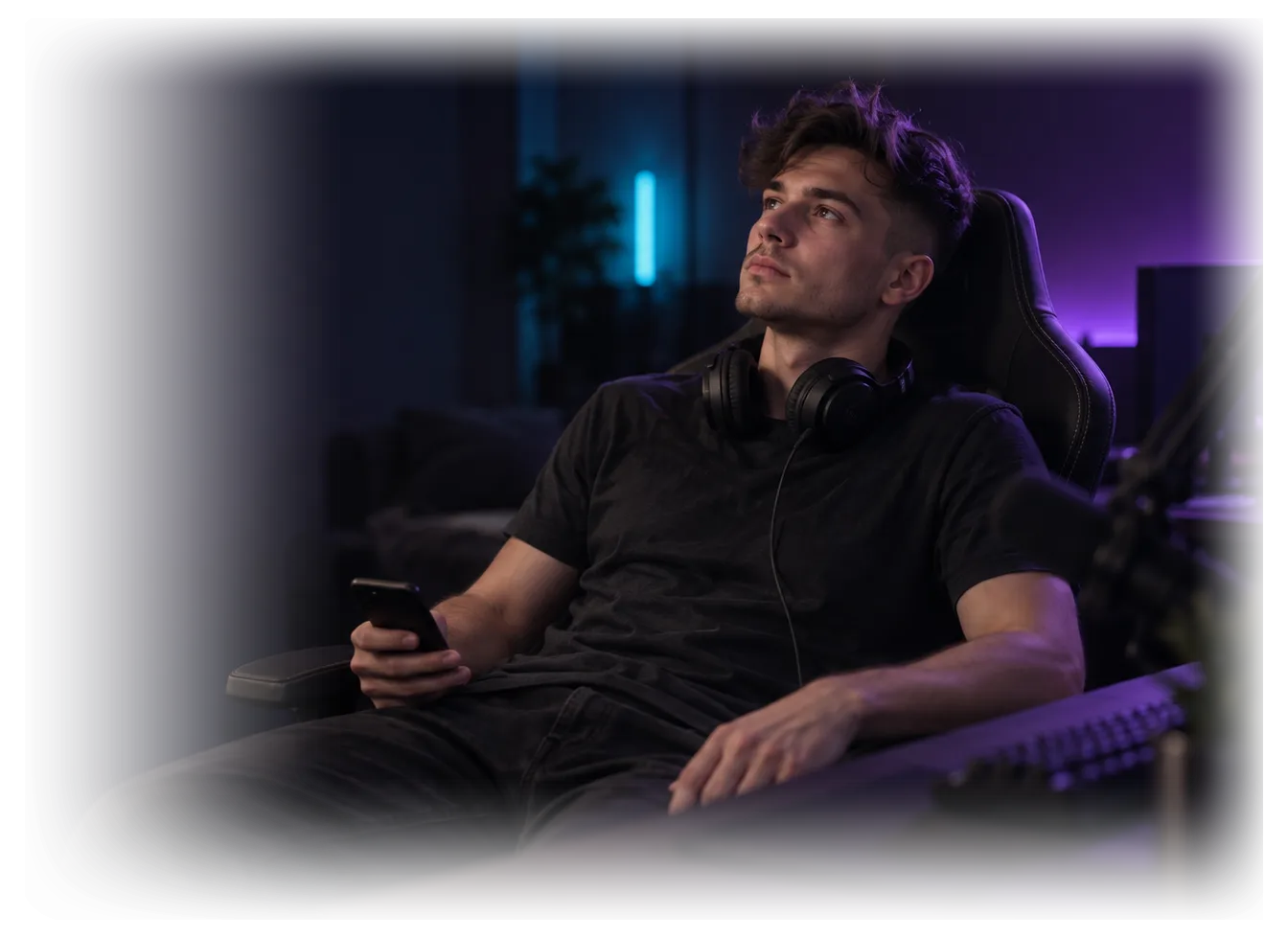 Ein Streamer lehnt sich in seinem Stuhl zurück, das Headset um den Hals, und blickt nachdenklich an der Kamera vorbei.